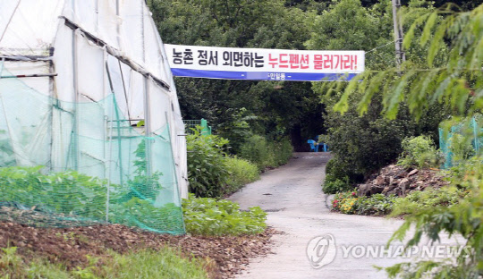 지난달 26일 오전 충북 제천시 봉양읍의 한 산골 마을 야산의 한 길목에 '누드족 물러가라'라고 적힌 현수막이 걸려있다. 이 마을을 에워싼 야산에는 '누디즘'을 표방하는 동호회 회원들의 휴양시설인 누드펜션이 운영되고 있다. <연합뉴스>